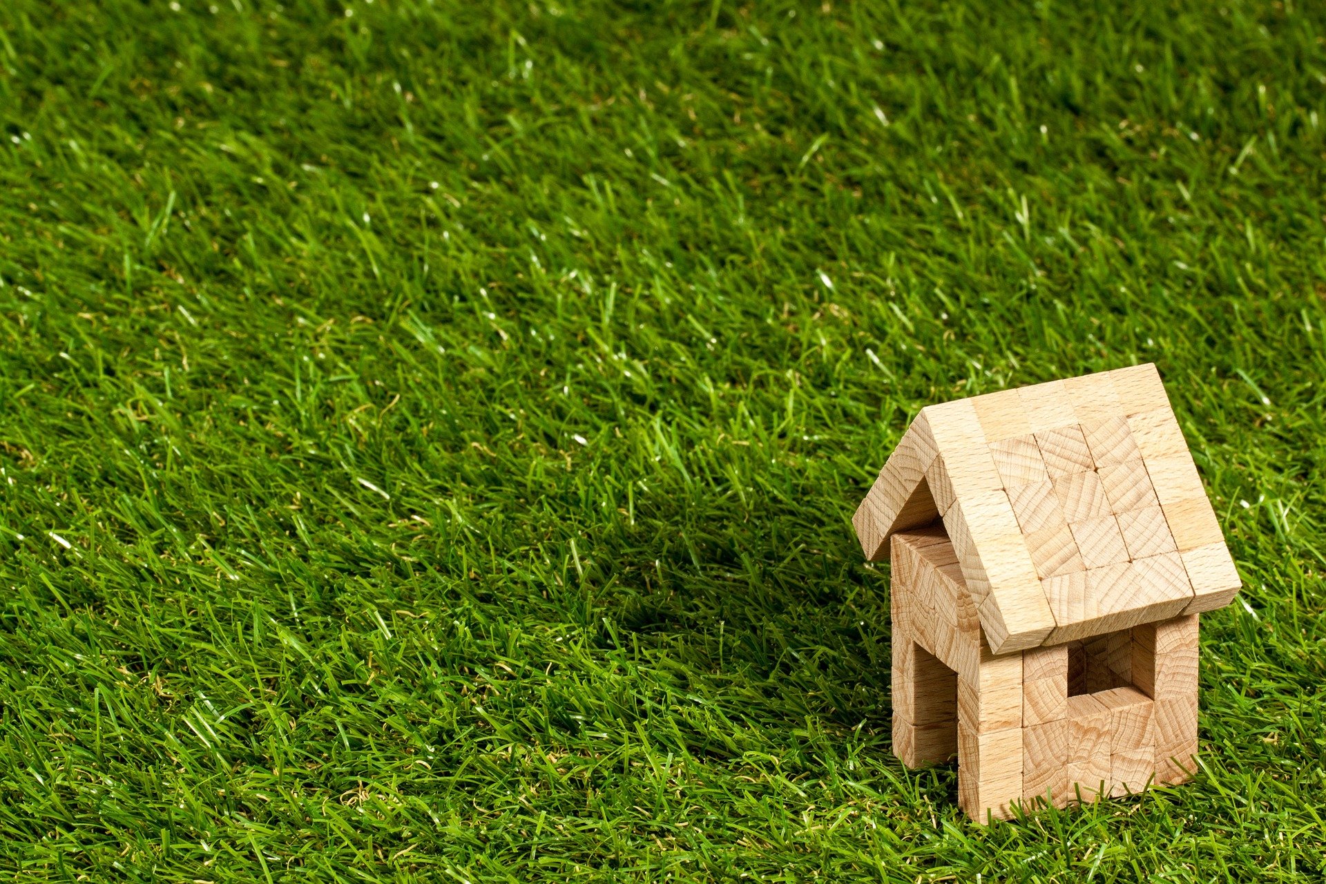 Sondereigentumsverwaltung in Hamburg und Stormarn - Frühling Immobilien kleines Haus aus Holzklötzen auf einer Rasenfläche
